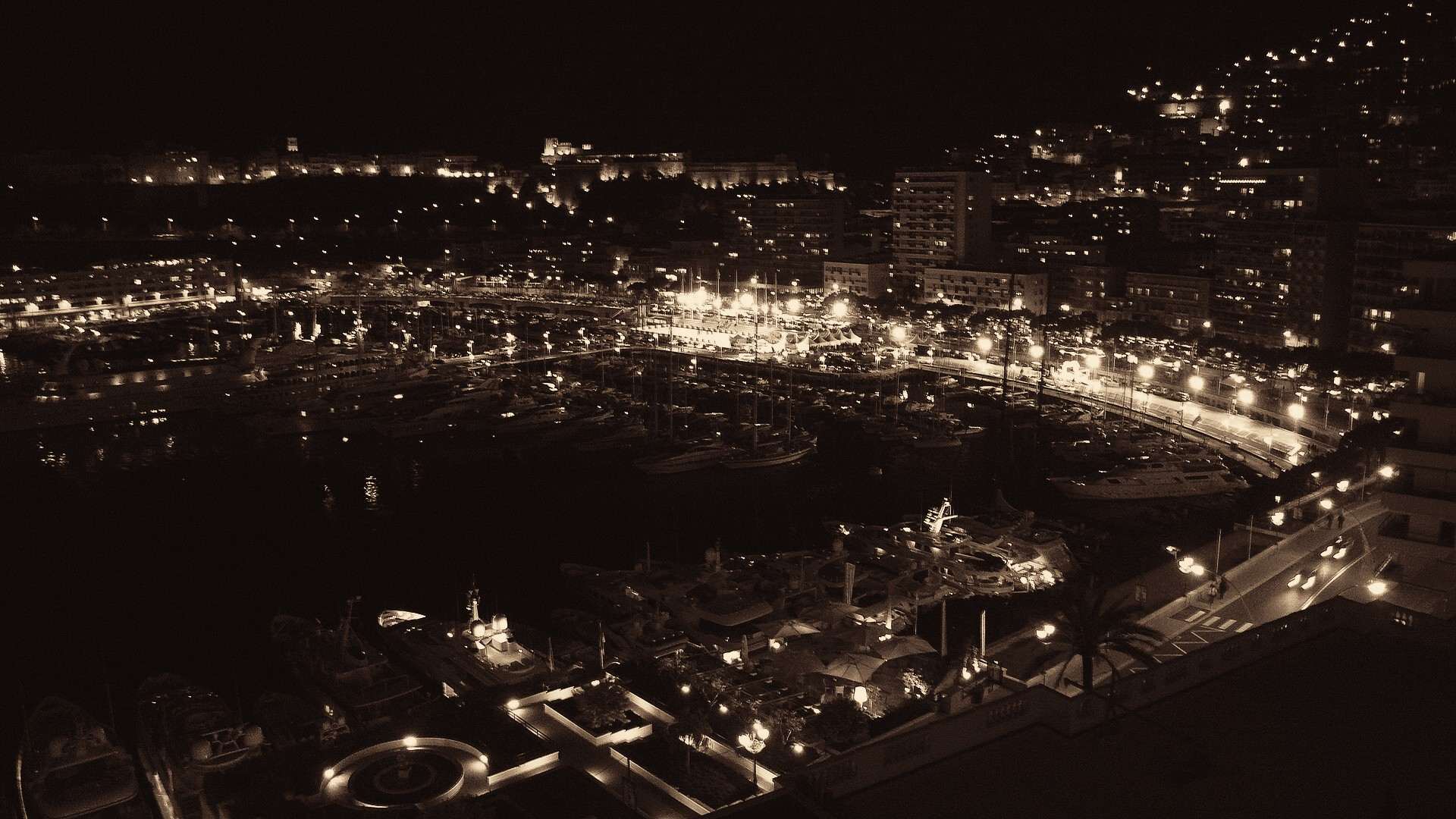The harbour of Monaco at night, yachts along the quays and the lights of Monte Carlo rising up the hillside