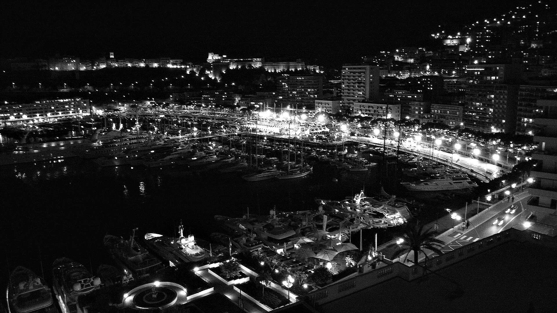 The harbour of Monaco at night, yachts along the quays and the lights of Monte Carlo rising up the hillside